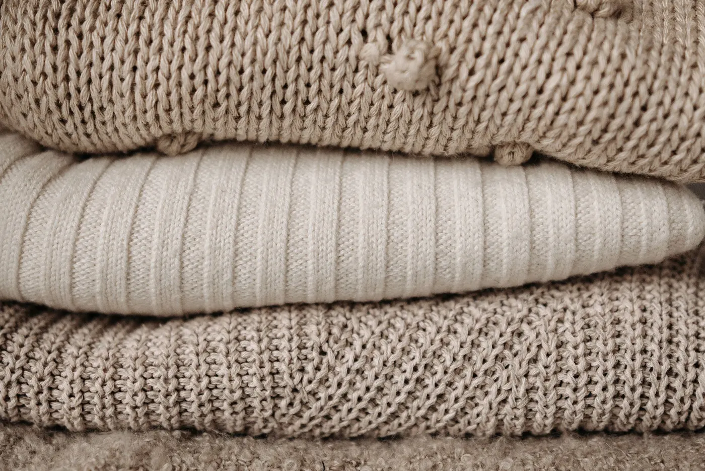 A neat stack of beige knitted sweaters